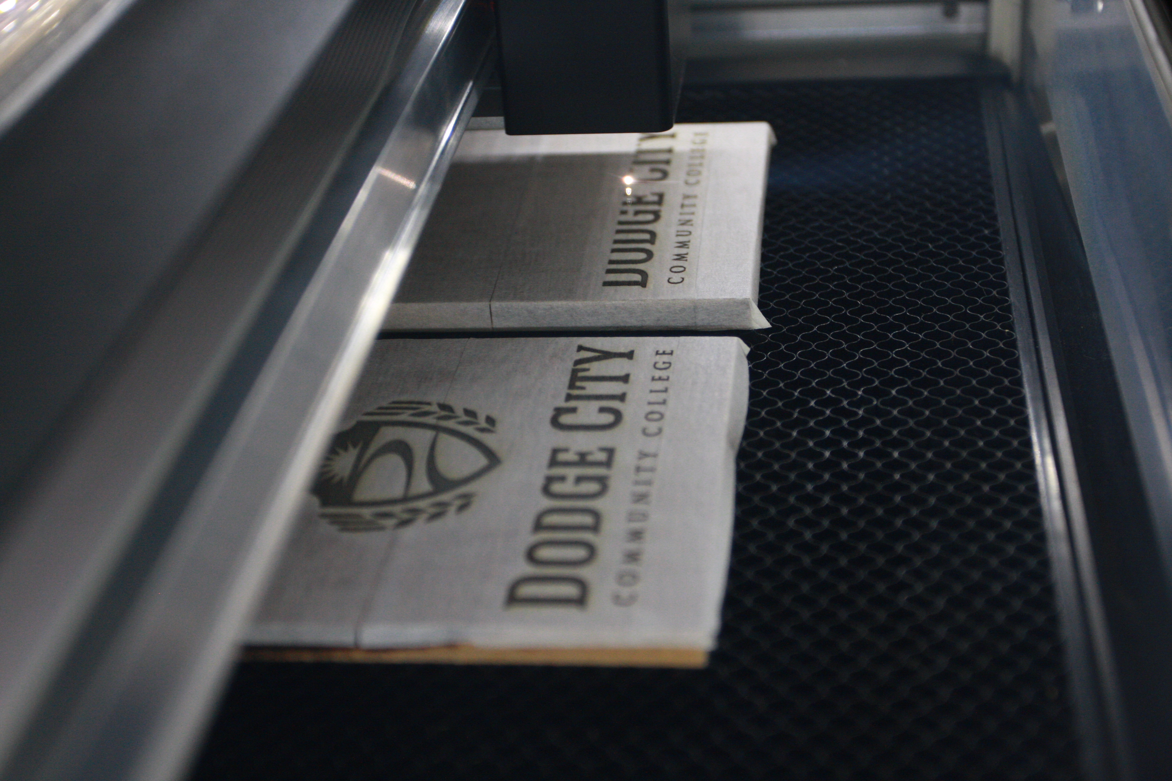 The Glowforge engraving wood tiles with the new DC3 academic logo
