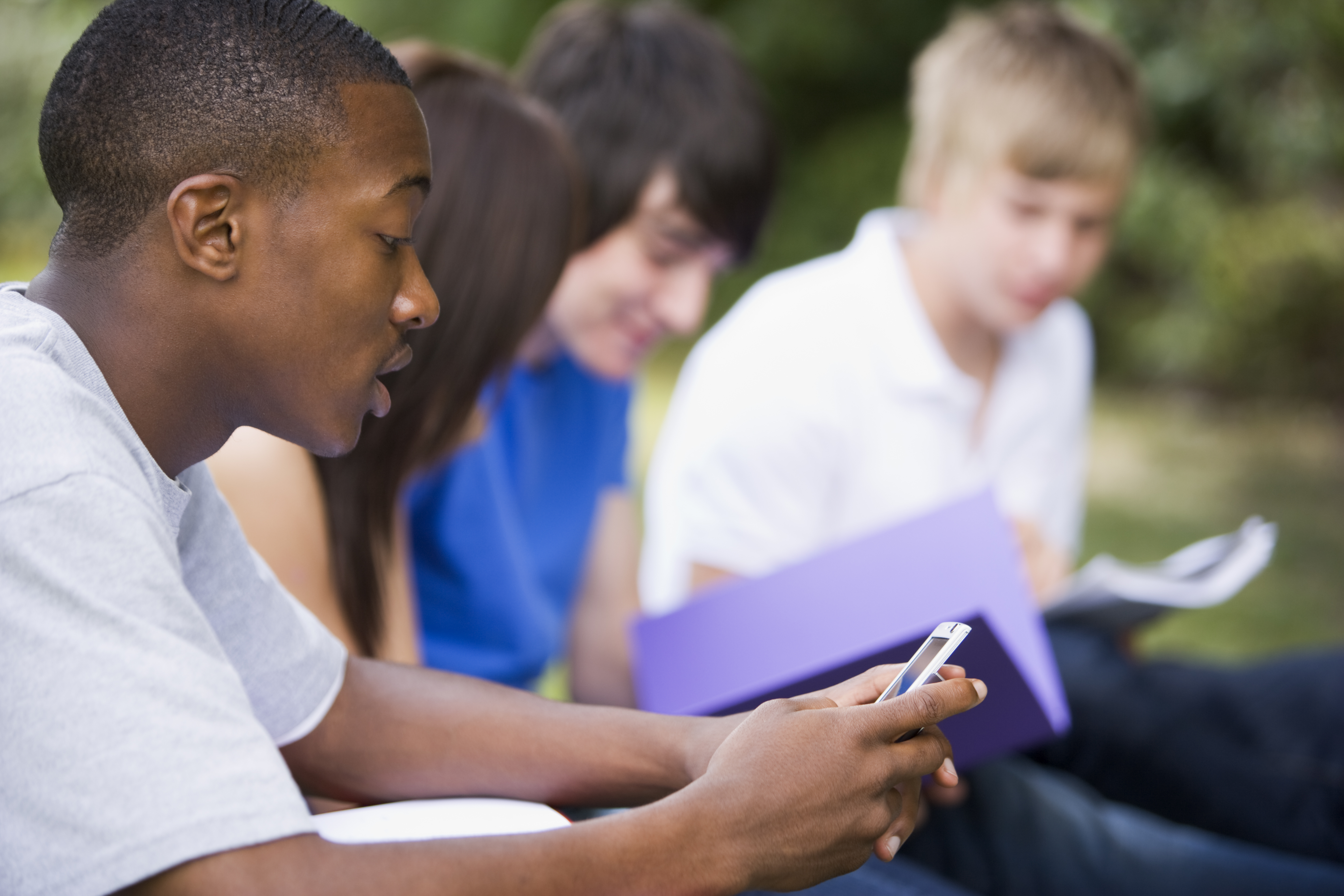 College students outside, one student is texting